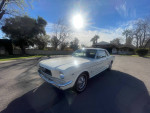 Classic 1966 Ford Mustang with Wimbledon white exterior and red interior, parked on a sunny street.