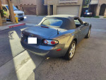 2007 Mazda MX-5 Sport convertible parked in residential area, showcasing its sleek design and soft top.