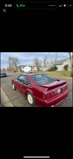 1990 Ford Mustang GT in maroon color, parked on street, showcasing no rust and classic design.