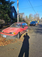 1990 Geo Metro parked on the street, showing salvage title, replaced parts, and visible wear.