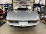 Front view of a 1980 Chevy Corvette in mint condition, displaying sleek design and bright headlights.