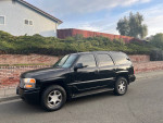 2006 GMC Yukon Denali AWD parked on street, showcasing its clean exterior and sleek design.
