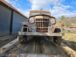 Front view of a 1953 Willys Jeep Truck on a trailer, showcasing its worn but complete body and classic design.