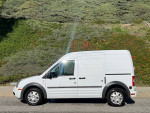 Side view of a 2010 Ford Transit Connect Cargo Van in white, showing clean exterior and tires.