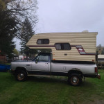 1989 Dodge Ram W250 4x4 truck with a camper shell, parked in a grassy area.