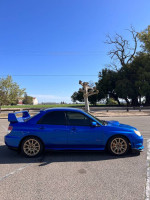 Side view of a blue 2007 Subaru Impreza STI parked outdoors, showcasing its sporty design and condition.