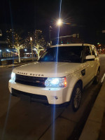 2012 Land Rover Range Rover Sport HSE parked at night with headlights on, showcasing its sleek design.