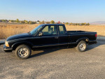 1999 GMC Sonoma SLS Sport 4WD, black pickup truck in need of repair, with visible exterior wear.