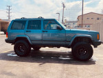 1999 Jeep Cherokee 4x4 with a lift kit and BFG All-terrain tires, parked in good condition.