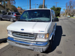 Front view of a 2000 Ford E-150 Triton camper van parked on the street, showcasing its clean exterior.