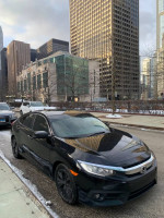 2016 Honda Civic EX-T Sedan parked on city street, showcasing its sleek black design and modern features.